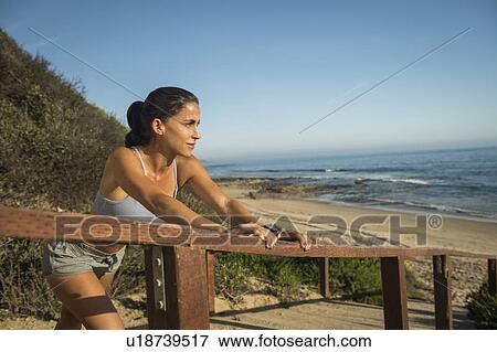 Stock Photo - USA, California, Newport Beach, Woman in sport suit looking at sea. Fotosearch
