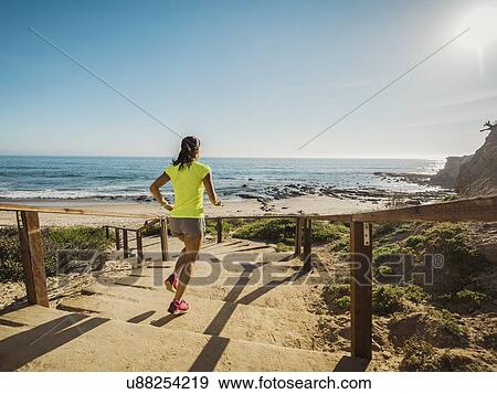 USA, California, Newport Beach, Woman running down stairs View Large Photo Image Stock Photo - USA, California, Newport Beach, Woman running down stairs. Fotosearch