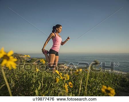 Stock Photograph - USA, California, Newport Beach, Woman stretching on cliff. Fotosearch