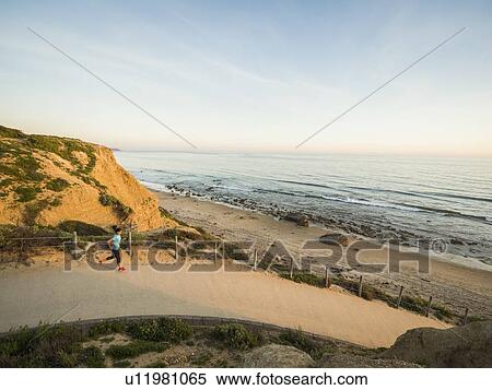 Stock Photography - USA, California, Newport Beach, Woman running along footpath. Fotosearch