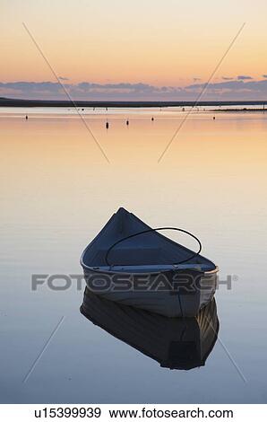 Stock Photo - USA, Massachusetts, Cape Cod, Chatham, Boat reflecting in water at dawn. Fotosearch