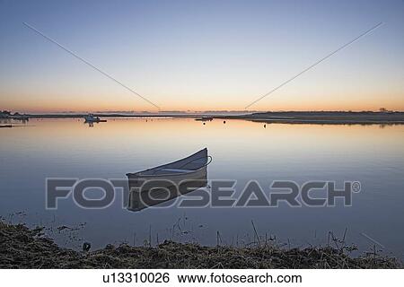 Stock Photograph - USA, Massachusetts, Cape Cod, Chatham, Boat reflecting in water at dawn. Fotosearch