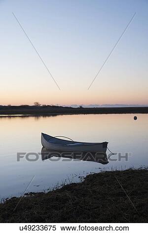 Stock Photography - USA, Massachusetts, Cape Cod, Chatham, Boat reflecting in water at dawn. Fotosearch