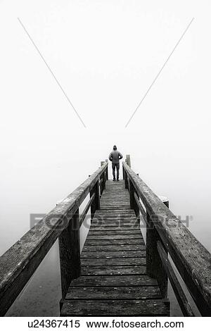 Stock Photography - USA, Massachusetts, Cape Cod, Eastham, Man standing on jetty in fog. Fotosearch