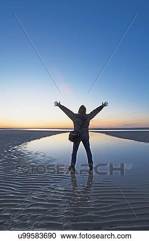 Stock Image - USA, Massachusetts, Cape Cod, Orleans, Man watching sunset at beach. Fotosearch