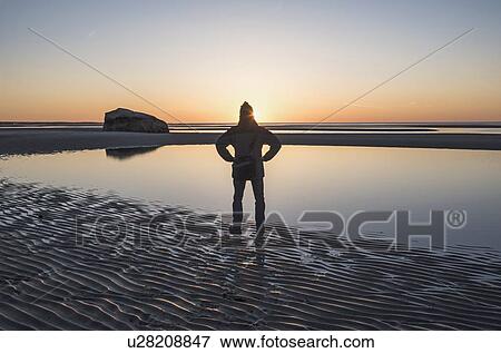 Stock Photo - USA, Massachusetts, Cape Cod, Orleans, Man watching sunset at beach. Fotosearch