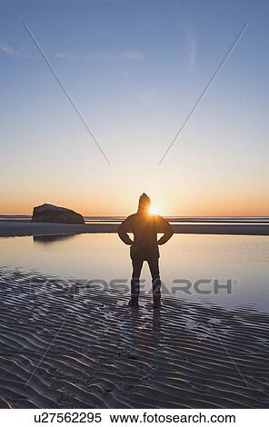 Stock Photography - USA, Massachusetts, Cape Cod, Orleans, Man watching sunset at beach. Fotosearch