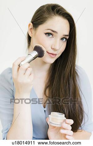 Stock Image - Woman applying make up with brush. Fotosearch
