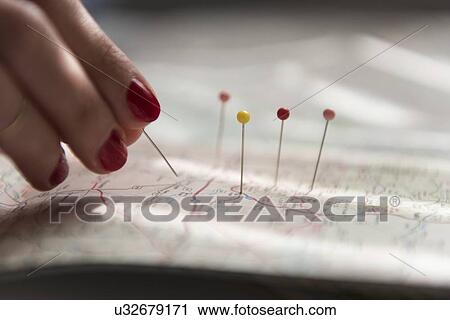 Stock Image - Woman applying pins on map. Fotosearch