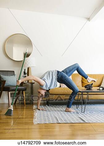 Stock Photo - Woman bending over backwards sweeping and dusting. Fotosearch