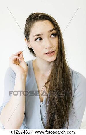 Stock Photo - Woman cleaning her ear with cotton bud. Fotosearch