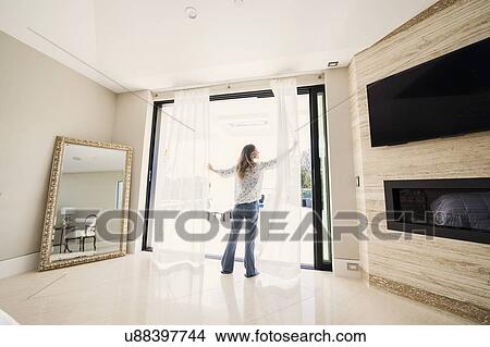 Woman drawing apart bedroom curtains View Large Photo Image Picture - Woman drawing apart bedroom curtains. Fotosearch