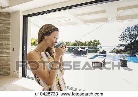 Stock Image - Woman drinking tea at home. Fotosearch
