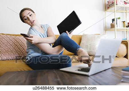 Stock Photography - Woman holding smart phone and folder while typing with foot. Fotosearch