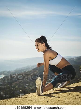 Picture - Woman in sportswear stretching on mountain. Fotosearch