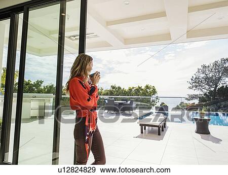 Stock Photo - Woman looking out of house window. Fotosearch