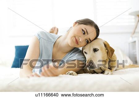 Woman lying on bed with dog View Large Photo Image Stock Image - Woman lying on bed with dog. Fotosearch