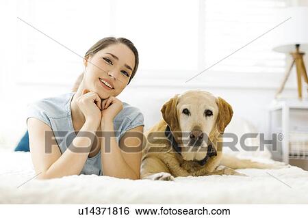 Woman lying on bed with dog View Large Photo Image Stock Photograph - Woman lying on bed with dog. Fotosearch