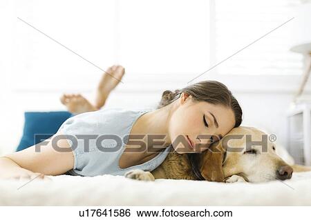 Woman lying on bed with dog View Large Photo Image Stock Photograph - Woman lying on bed with dog. Fotosearch