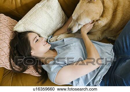 Woman lying on sofa with dog View Large Photo Image Stock Image - Woman lying on sofa with dog. Fotosearch