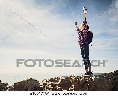 Picture - Woman on hike with arms raised. Fotosearch