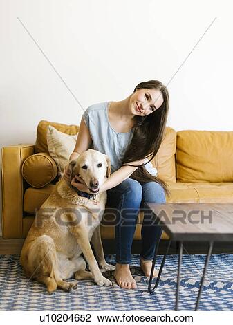 Stock Image - Woman on sofa with dog. Fotosearch