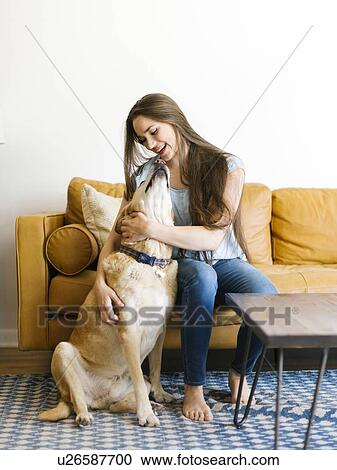 Stock Image - Woman on sofa with dog. Fotosearch