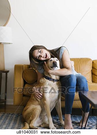 Stock Image - Woman on sofa with dog. Fotosearch