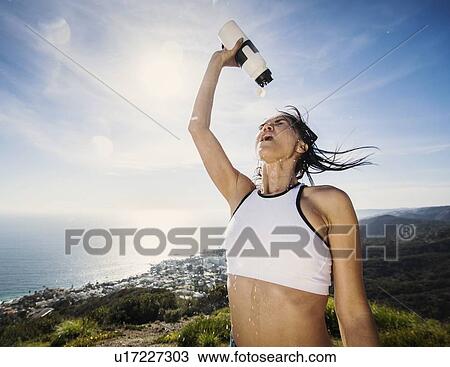 Stock Image - Woman pouring water on her head. Fotosearch