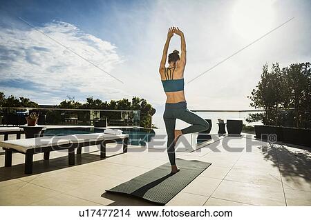 Woman practicing yoga by swimming pool View Large Photo Image Picture - Woman practicing yoga by swimming pool. Fotosearch