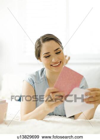 Woman putting card into envelope on bed View Large Photo Image Stock Photo - Woman putting card into envelope on bed. Fotosearch