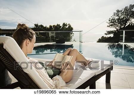 Woman reading book by swimming pool View Large Photo Image Stock Photography - Woman reading book by swimming pool. Fotosearch