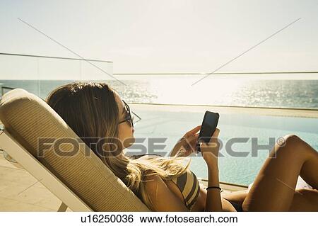 Woman relaxing by swimming pool by ocean View Large Photo Image Stock Photograph - Woman relaxing by swimming pool by ocean. Fotosearch
