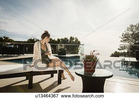 Woman relaxing by swimming pool View Large Photo Image Stock Photo - Woman relaxing by swimming pool. Fotosearch