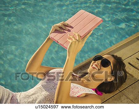 Stock Photo - Woman using digital tablet by swimming pool. Fotosearch