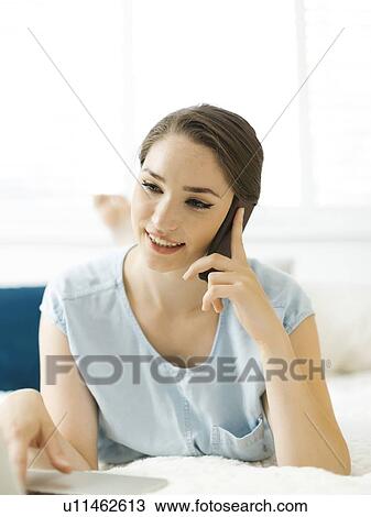 Woman using laptop and smart phone on bed View Large Photo Image Stock Image - Woman using laptop and smart phone on bed. Fotosearch