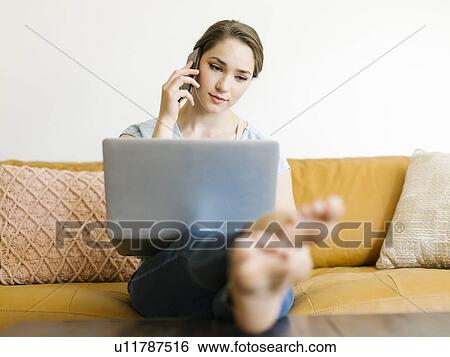 Woman using laptop and smart phone on sofa View Large Photo Image Stock Photograph - Woman using laptop and smart phone on sofa. Fotosearch