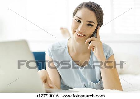 Woman using laptop and smart phone on bed View Large Photo Image Stock Photograph - Woman using laptop and smart phone on bed. Fotosearch