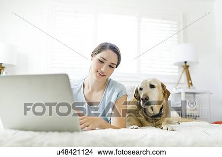 Woman using laptop with dog View Large Photo Image Picture - Woman using laptop with dog. Fotosearch