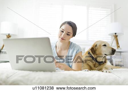 Woman using laptop with dog View Large Photo Image Stock Photo - Woman using laptop with dog. Fotosearch