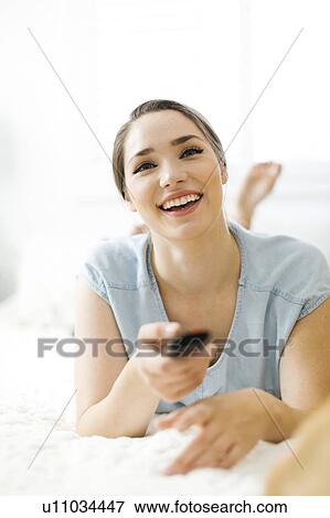 Woman using remote control on bed View Large Photo Image Stock Photo - Woman using remote control on bed. Fotosearch
