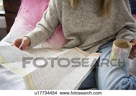 Picture - Woman with map and coffee in armchair. Fotosearch