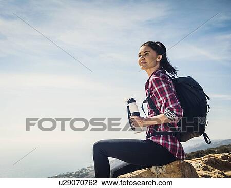 Woman with water bottle sitting on rock View Large Photo Image Stock Image - Woman with water bottle sitting on rock. Fotosearch