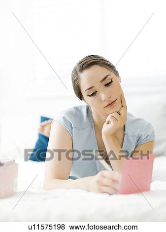 Woman writing in card on bed View Large Photo Image Stock Photo - Woman writing in card on bed. Fotosearch