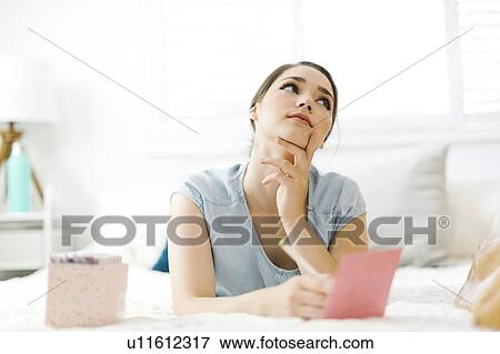Stock Photo - Woman writing in card on bed. Fotosearch