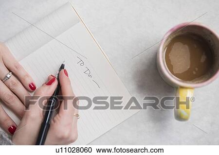 Stock Image - Woman writing in notepad. Fotosearch