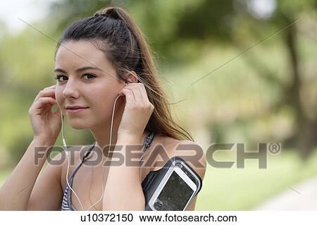 Young woman adjusting headphones during exercise View Large Photo Image Stock Image - Young woman adjusting headphones during exercise. Fotosearch