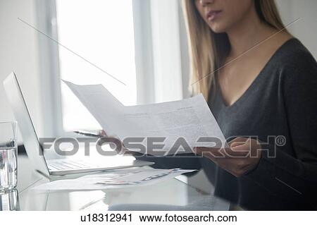 Stock Image - Young woman doing paper work. Fotosearch