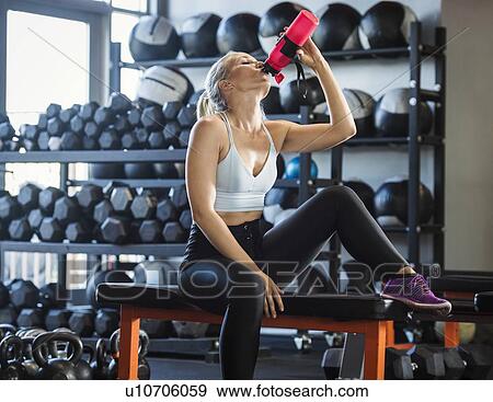 Young woman drinking in gym View Large Photo Image Stock Photo - Young woman drinking in gym. Fotosearch
