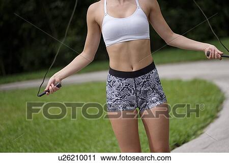 Stock Image - Young woman exercising with jump rope. Fotosearch